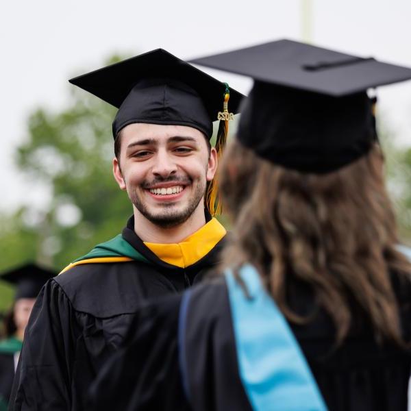 Student at graduation wearing cap and gown. 